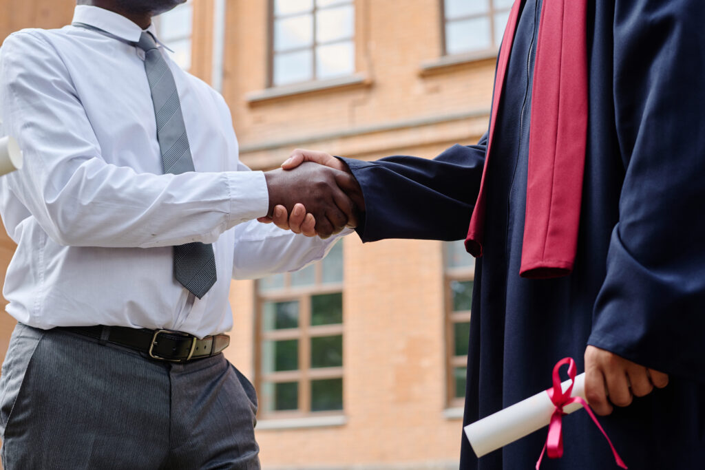 Diploma in hand and a professional handshake, capturing the promise of new graduate employment opportunities.